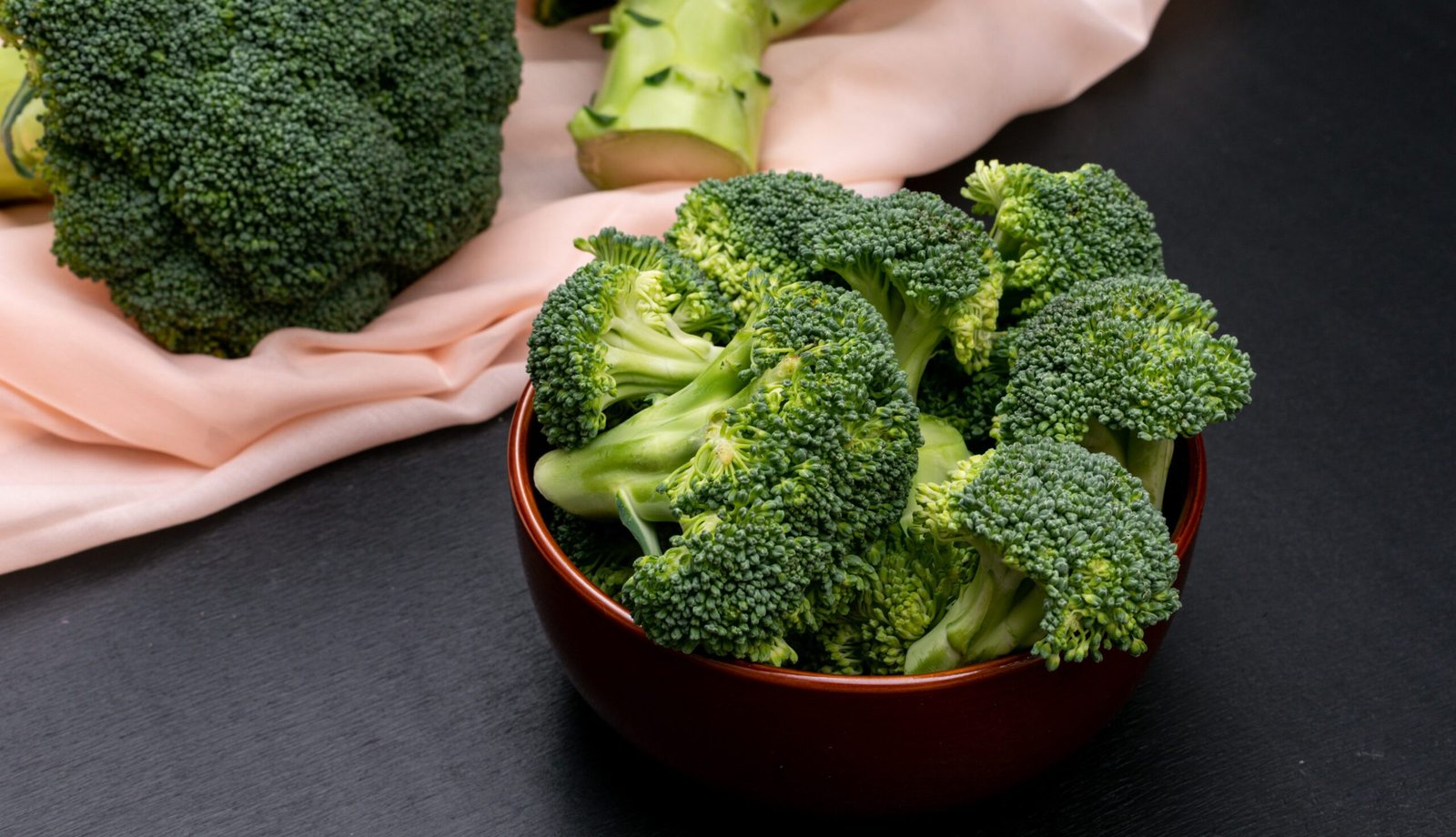 broccoli in ceramic bowl and on pink cloth